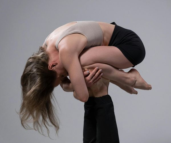 Man in a warrior yoga pose on a mat in a minimalist studio.
